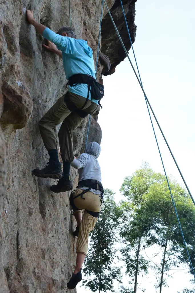 Two climbers ascending volcanic rock cliffs at the rock climbing spot near Sipi Falls in Eastern Uganda with professional safety gears