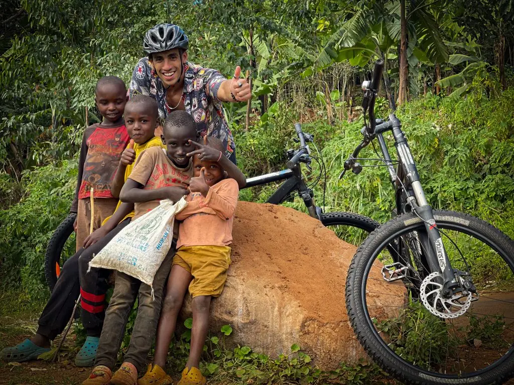 Mountain cyclist posing with local children beside bicycles along the Sipi Falls cycling trail near Mount Elgon,Uganda