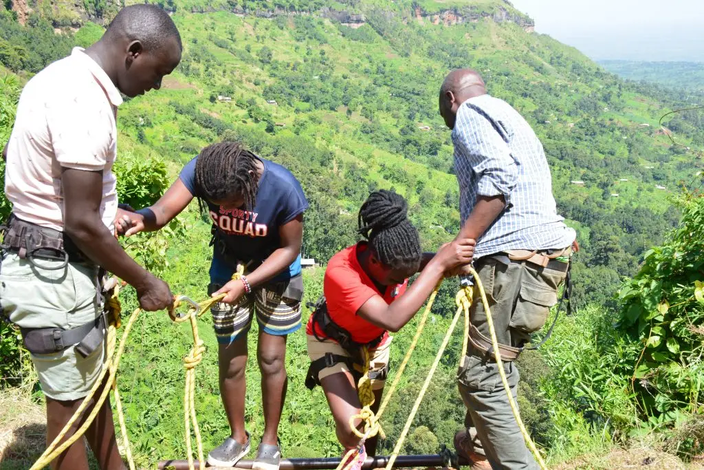 Local guides assisting tourists during abseiling at Sipi Falls
