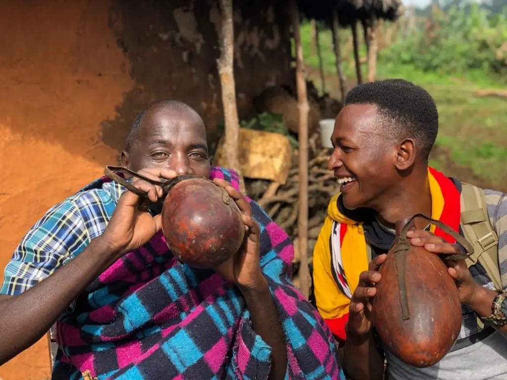 Ndorobo community member sharing traditional drinks with our guide, William during a cultural experience on the Ndorobo Nature Trail near Mount Elgon